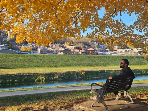 Anwar on a park bench under autumn leaves